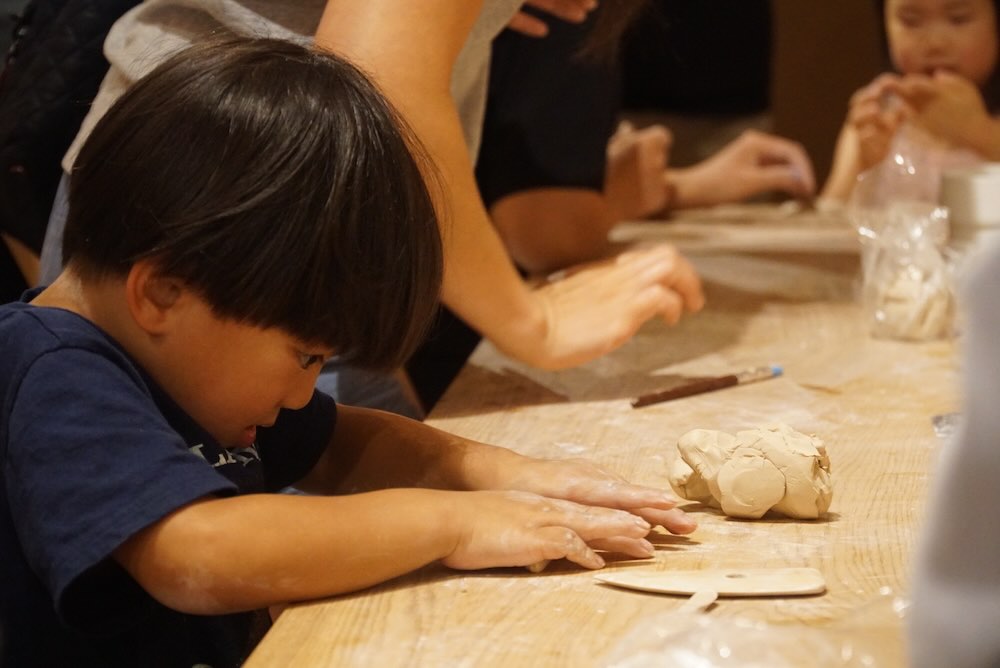Kids and teens working with clay at the pottery table during summer camp at Olomana Studios in Irvine