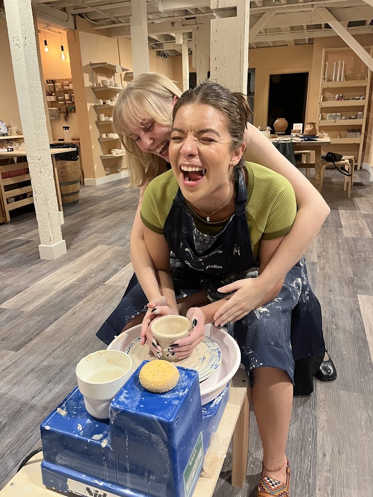 Two friends laughing during a pottery class at Olomana Studios