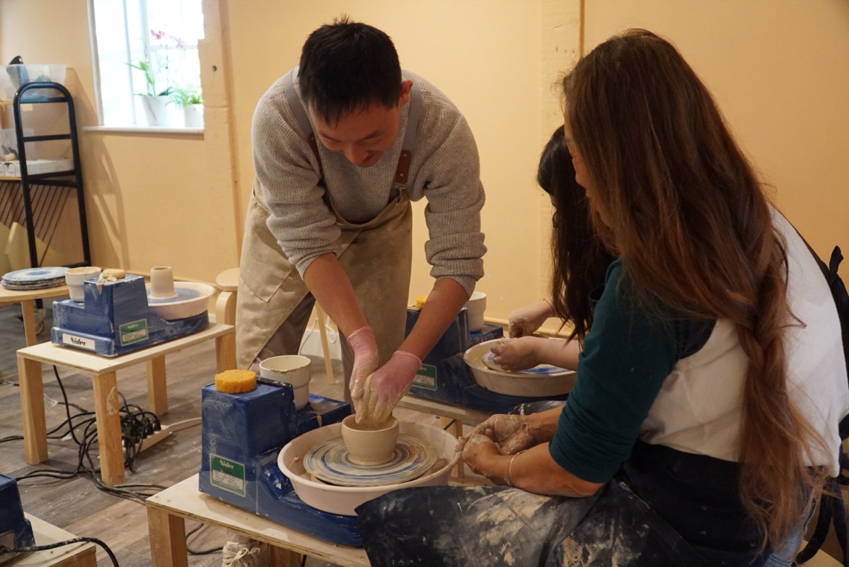 Instructor helping a student one-on-one at the pottery wheel